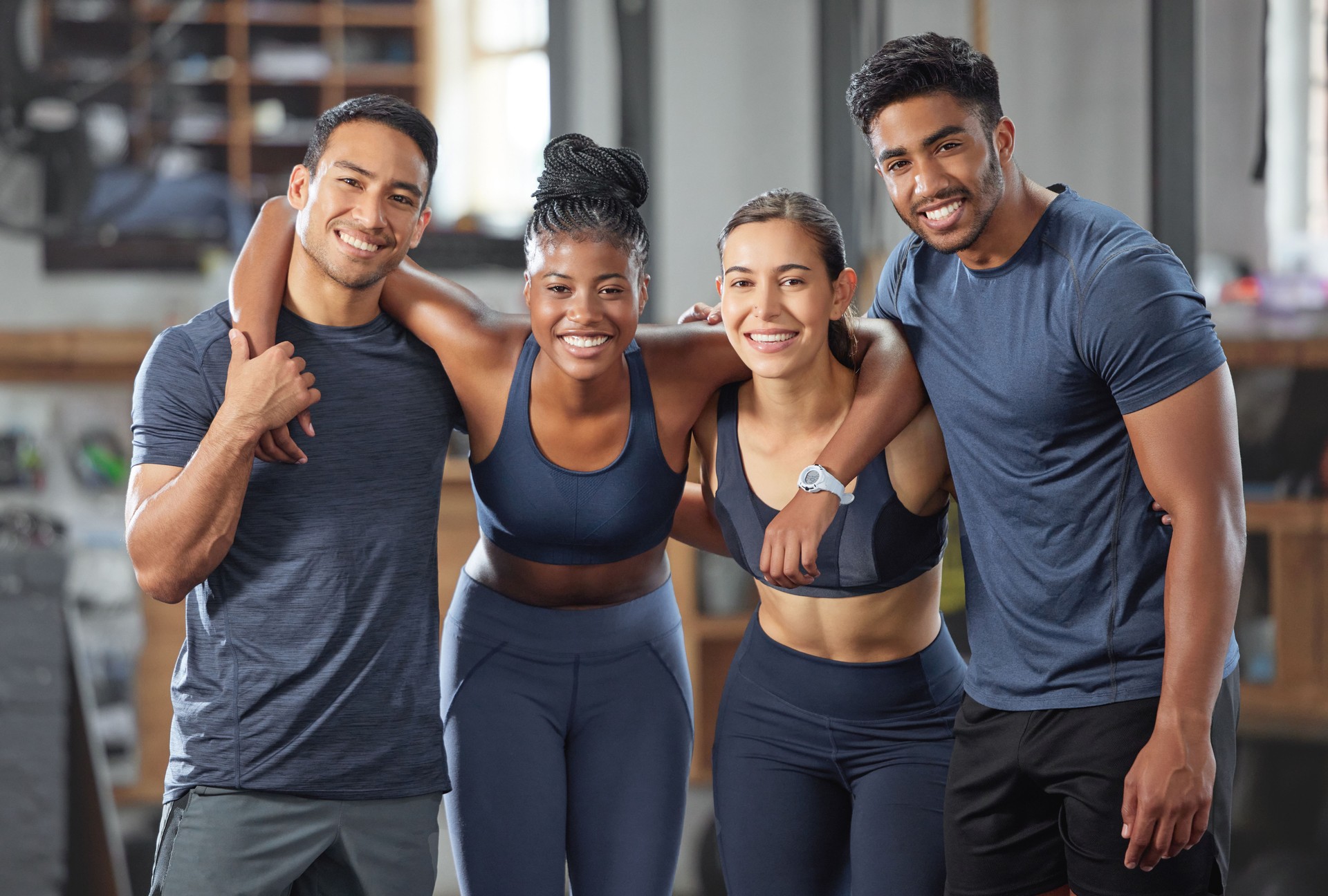 Fitness, exercise and diverse accountability group standing together and looking happy after training at gym. Portrait of friends enjoying their membership at a health and wellness facility
